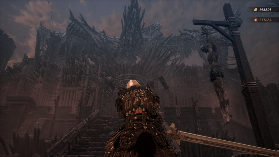 A dark and ominous scene from a fantasy video game. A figure clad in dark armor stands at the bottom of a long stone staircase, facing a huge, jagged castle made of dark stone. To the right, a crucified figure hangs on a wooden cross, silhouetted against the castle and sky. The overall atmosphere is foreboding and oppressive with a cloudy sky contributing to the dark mood and the indication of the user having currency at the top right corner.