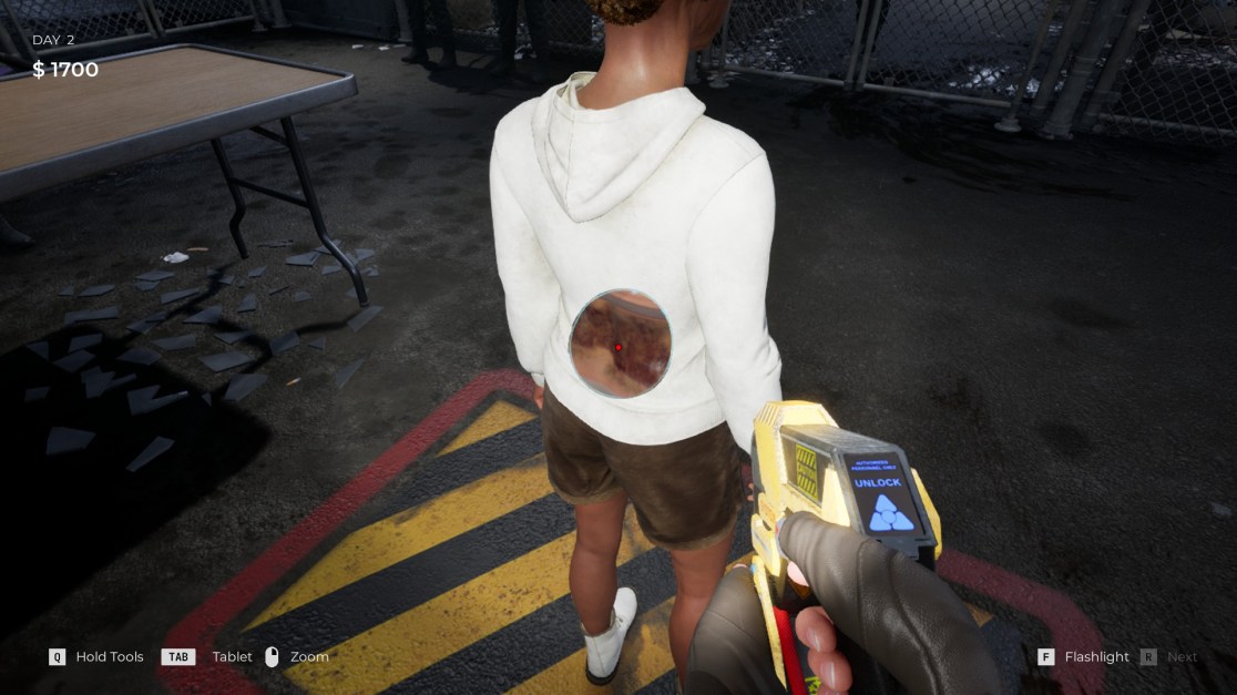 screenshot showing a person from the back, wearing a white hoodie with a large, scanner revealing hidden symptoms. The person is standing in an urban environment with debris, holding a yellow and black scanner. Game interface elements indicate it's "Day 2" with "$1700" earned, and prompts for "flashlight" and other actions.