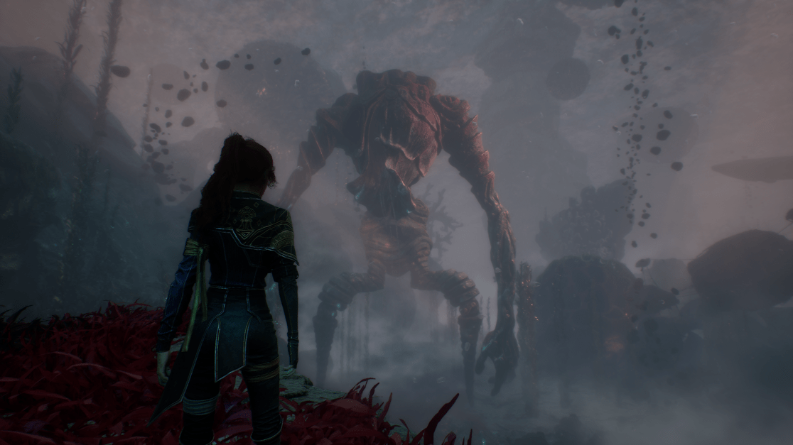 From behind, a woman in dark, ornate clothing stands overlooking a misty landscape. In the distance, a towering, monstrous figure with red, armored plating and elongated limbs looms through the fog. The foreground features red alien-like plants, enhancing the otherworldly atmosphere. The scene creates a sense of impending danger and tension.