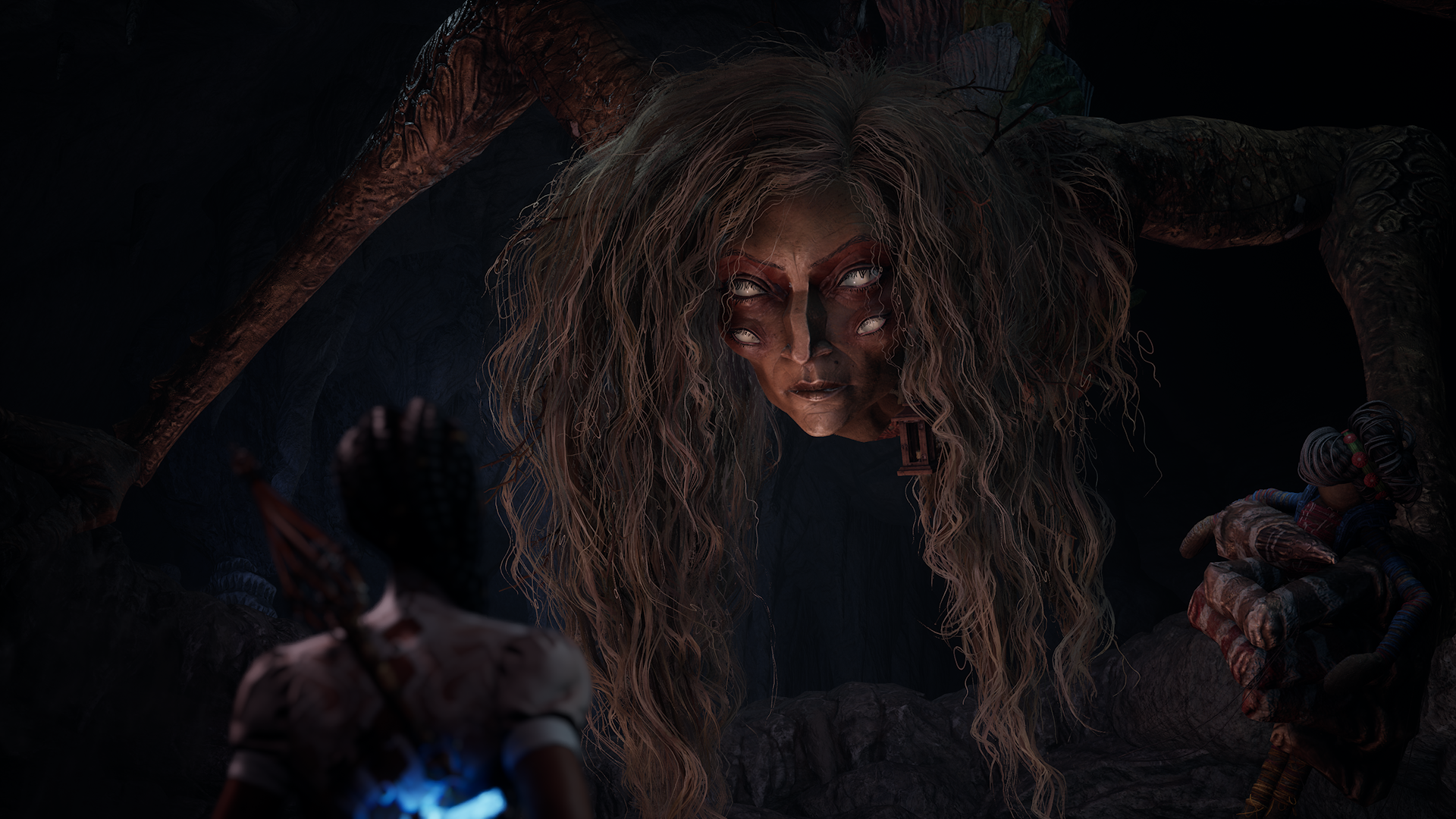 In a shadowy, cavern-like setting, a massive spider-like creature with flowing hair and multiple legs looms overhead. Below it, a character with braided hair stands ready, gripping a weapon. Nearby, another figure sits on the ground wrapped in vibrant, multicolored fabric. The eerie lighting and surreal creature design evoke a tense, fantastical atmosphere typical of South of Midnight’s Southern Gothic style.